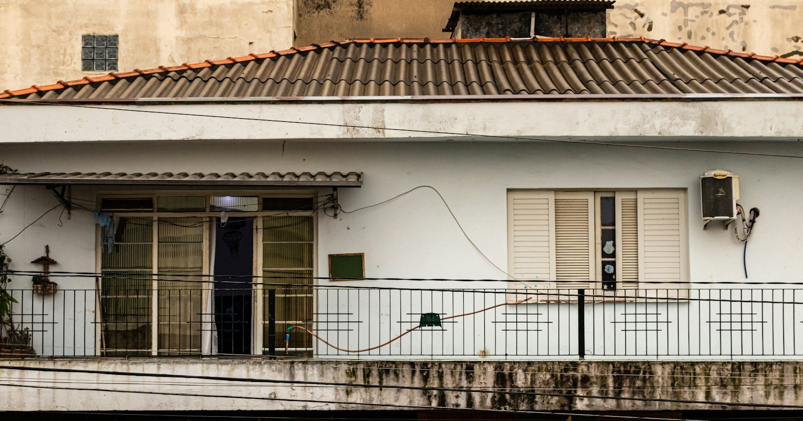 Fachada de casa térrea com telhado de cerâmica e varanda gradeada