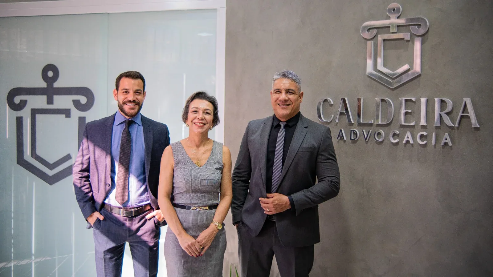 Equipe da Caldeira Advogados Associados diante do logotipo do escritório