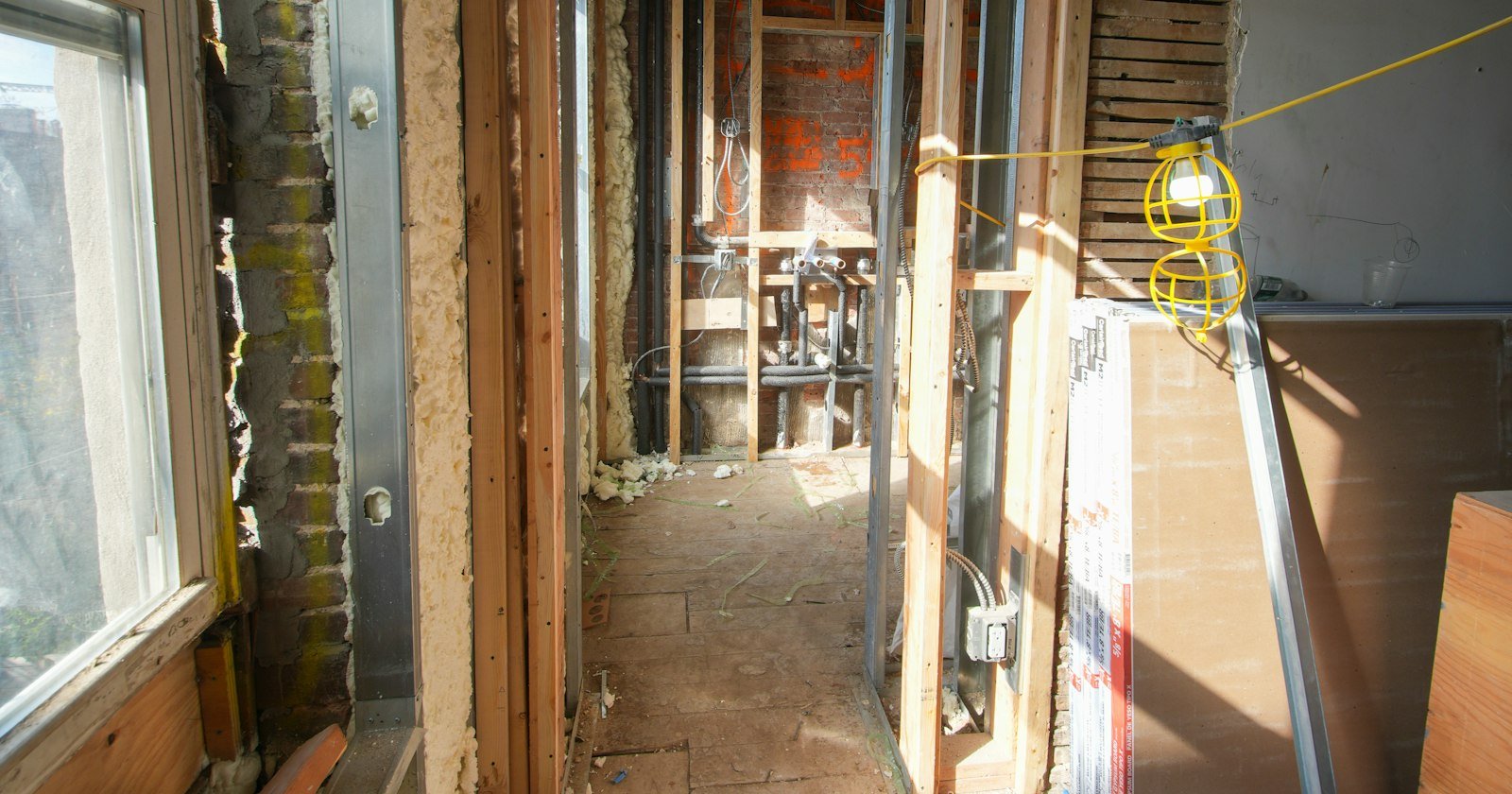 Interior de uma casa em construção, com estrutura aparente e paredes ainda sem acabamento