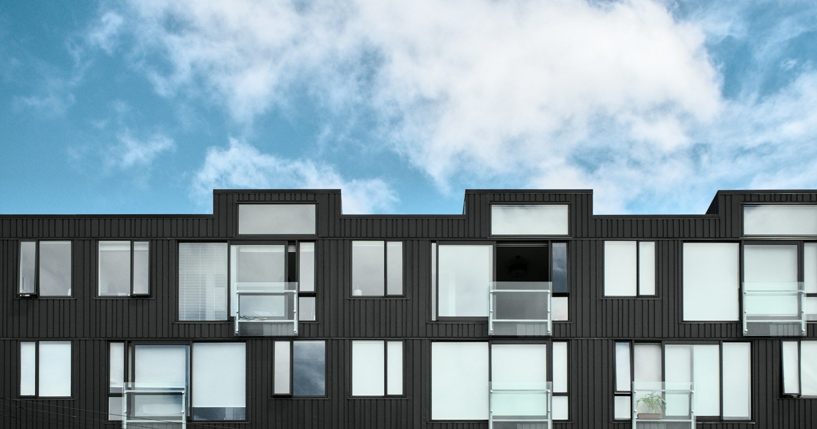 Prédio residencial novo de poucos andares, com janelas de esquadria escura
