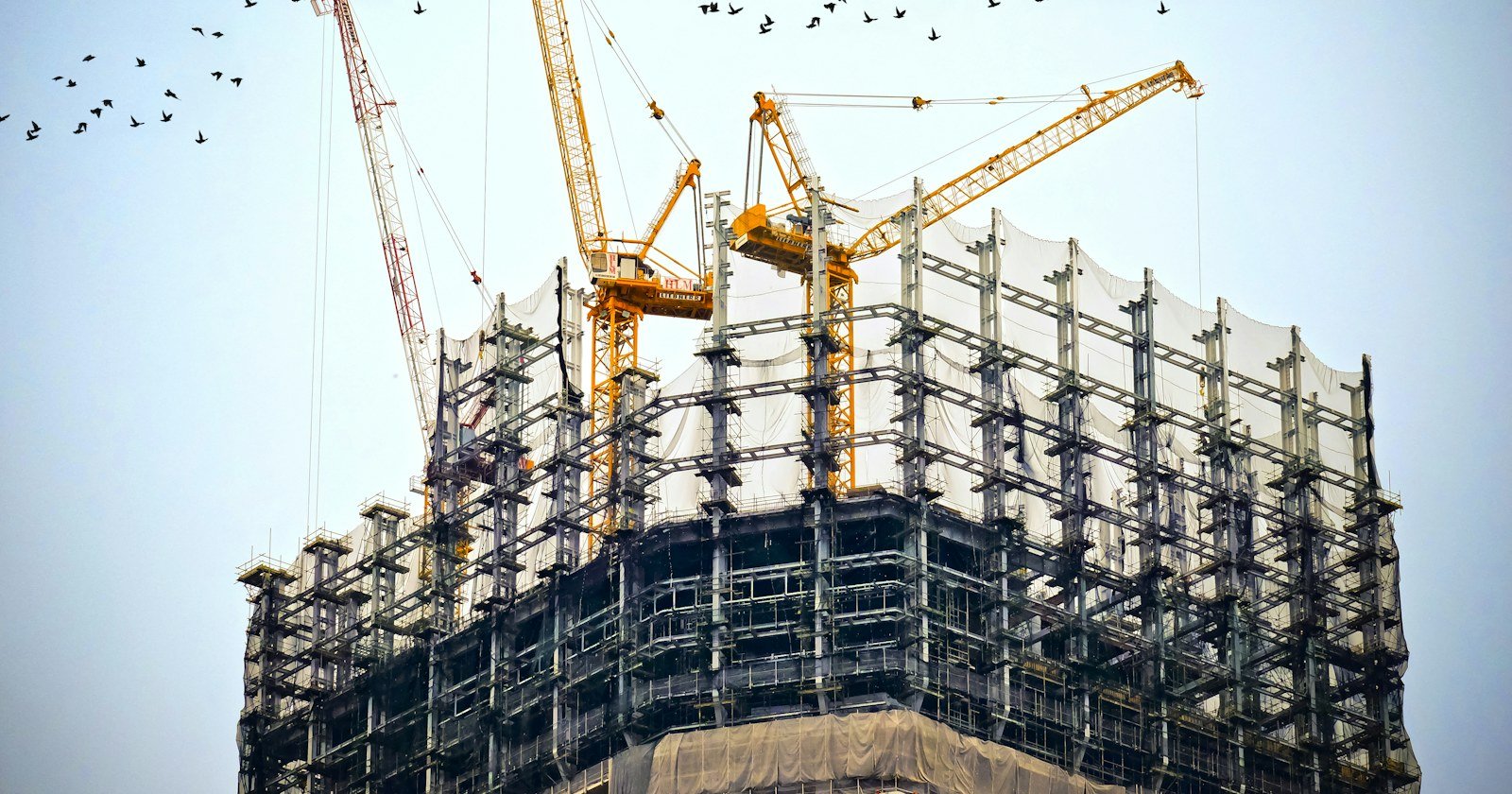 Prédio em construção com guindastes, ilustrando o memorial de incorporação