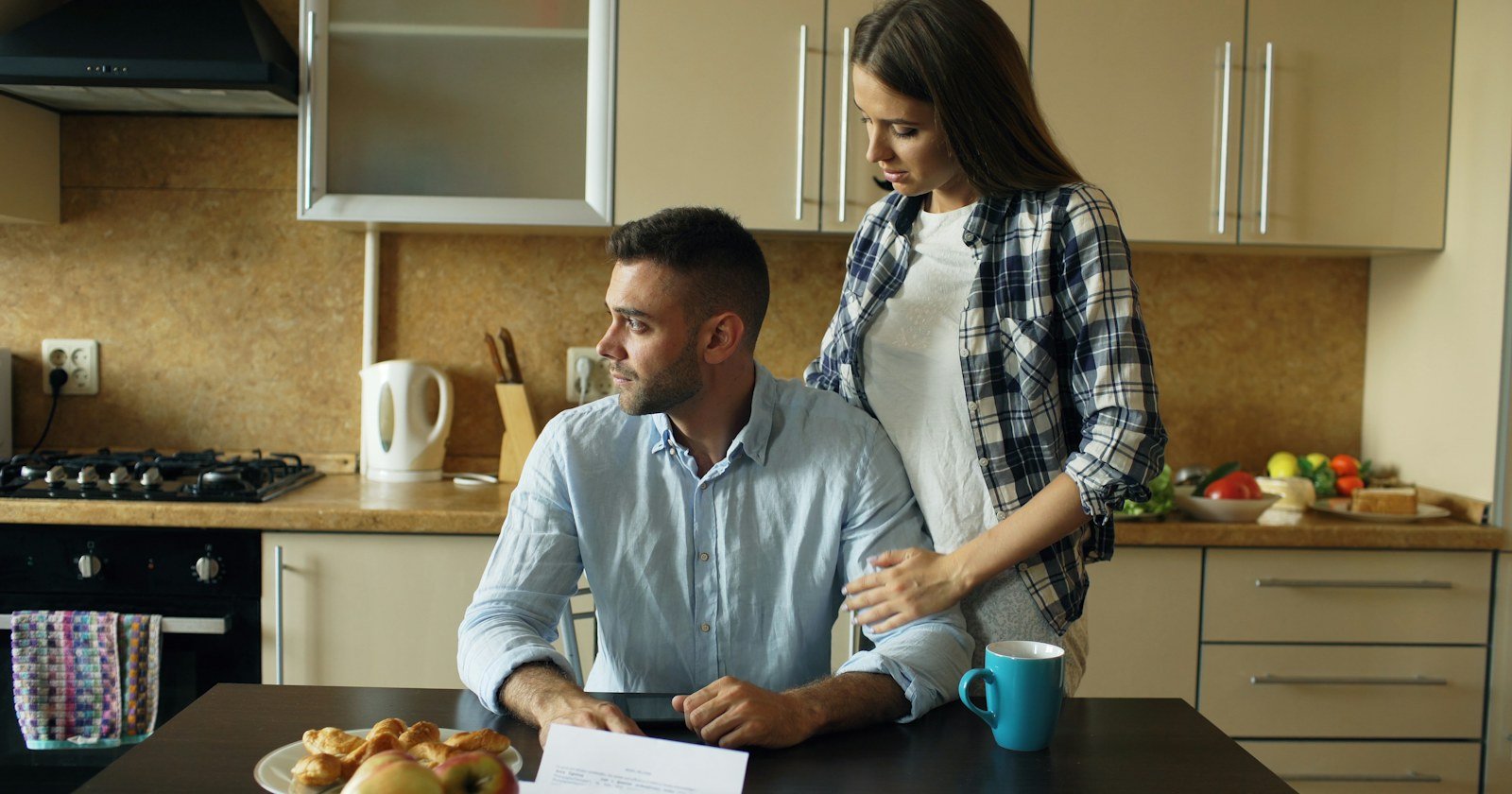 Casal conversando à mesa da cozinha com papéis, ilustrando a partilha de imóvel financiado no divórcio