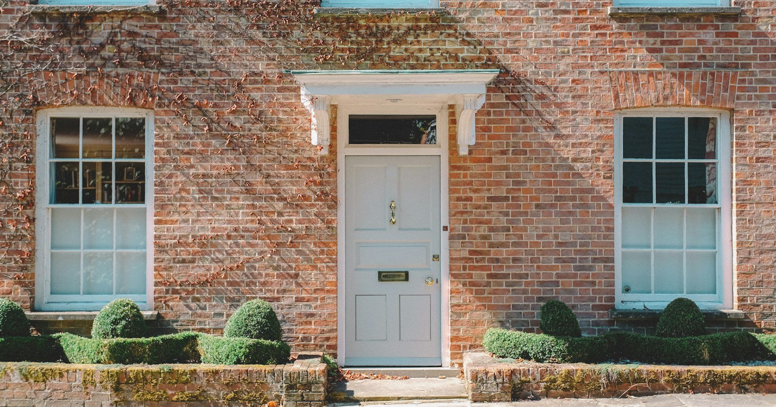 Fachada de casa de tijolos com porta branca, ilustrando a usucapião de imóvel com hipoteca ou penhora