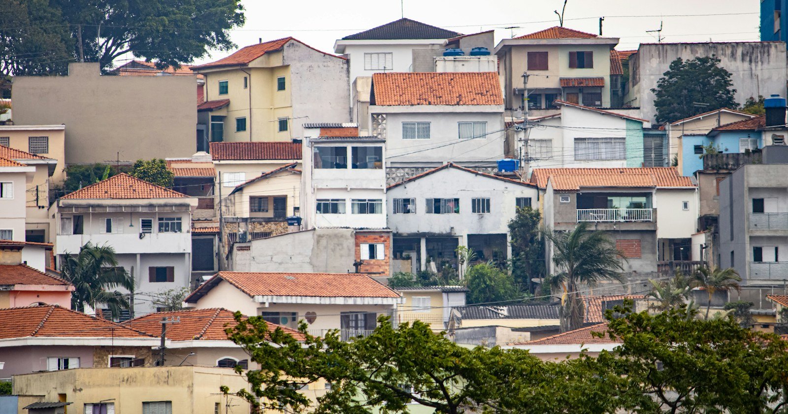 Casas de vários andares construídas lado a lado em uma encosta urbana